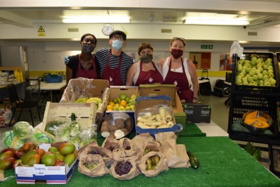 community pantry volunteers standing behind a table of fresh fruit and vegetables